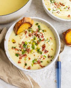 two bowls filled with soup next to bread