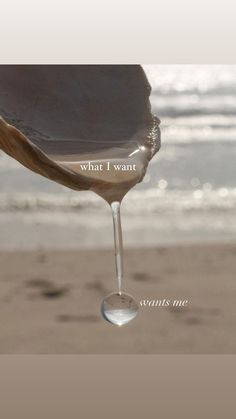 a drop of water hanging from the side of a sandy beach next to the ocean