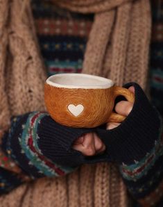 a person holding a coffee cup with a heart on the inside and in their hands