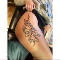 a woman's thigh with a tattoo on it and flowers in the middle of her leg