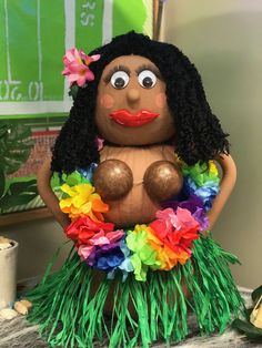 a woman in a hula skirt sitting on top of a table next to a potted plant