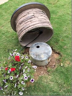 a spool of wire sitting on top of a grass covered field next to a flower pot