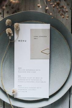 the menu card is placed on top of the plate, with dried flowers in front of it