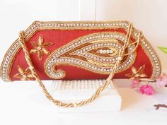 "A red clutch bag with gold bead trim. The statement handbag has a background of red taffeta, this is a brownish red. The front flap has a stunning design of gold and copper beading with rhinestones. The bag interior is red with one zipper pocket and a snap closure. The red beaded clutch also includes a beaded strap to wear on shoulder. This is a dazzling special occasion bag. It is large enough to hold an iPhone. MATERIAL: Beading, taffeta CONDITION: Good SIZE: 11\" wide and45: high COLOR: Brow Red Embellished Rectangular Bag, Red Embellished Bag For Formal Occasions, Red Embellished Clutch For Formal Occasions, Elegant Red Beaded Clutch, Formal Red Embellished Bag, Embroidered Red Pouch Clutch, Red Embroidered Pouch Clutch, Red Beaded Clutch For Party, Red Rectangular Bag For Celebration