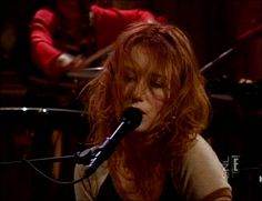 a woman with red hair is singing into a microphone