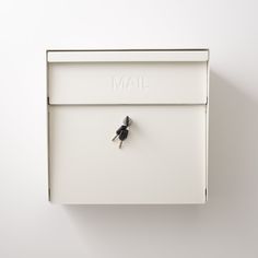 a white mailbox mounted to the side of a wall with a small black bird on it