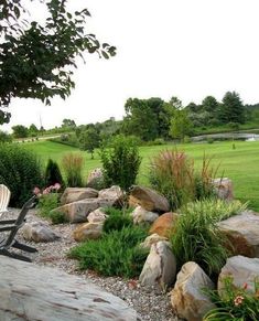 a lawn chair sitting on top of a pile of rocks next to a lush green field