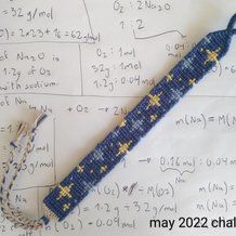 a blue and yellow beaded object on top of a sheet of paper with writing