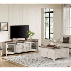 a living room filled with furniture and a flat screen tv on top of a wooden table