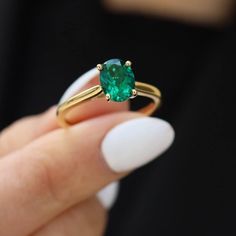 a woman holding an emerald ring in her hand