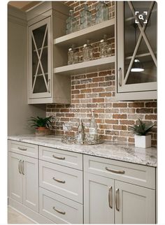 a kitchen with white cabinets and brick wall