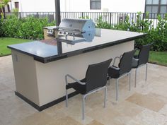 an outdoor kitchen with four chairs around it