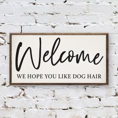 a sign that says, welcome we hope you like dog hair on the side of a brick wall