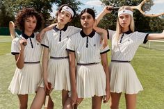 four girls in tennis uniforms are holding rackets