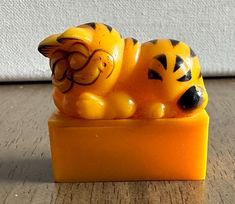 a yellow and black tiger figurine sitting on top of a block of soap