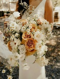 a bride holding a bouquet of white and orange flowers