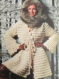 a woman wearing a white crocheted coat with a fur collar