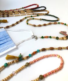 several beaded necklaces with tassels and beads on a white table top