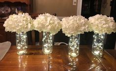 three clear vases with white flowers in them