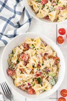 two white bowls filled with pasta salad and topped with tomatoes, parmesan cheese and fresh herbs