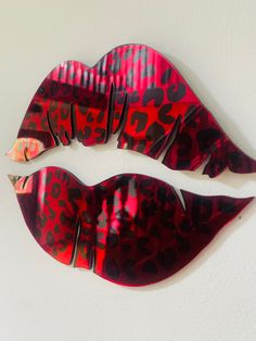 two red lips with black spots on them are shown against a white wall and one is shaped like an animal print