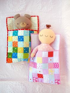 two stuffed animals laying next to each other on top of a white bed sheet covered in pink and blue checkered sheets