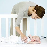 a woman is playing with a baby in her crib