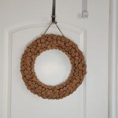 a wreath made out of wine corks hangs on the front door's white door