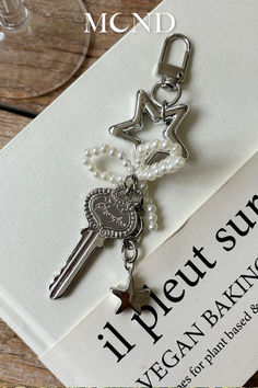 a keychain with pearls and keys attached to it sitting on top of a piece of paper