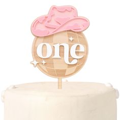 a cake topper with the word one on it and a pink hat sitting on top