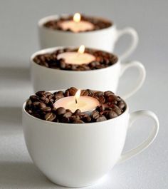 three cups filled with coffee beans and lit candles