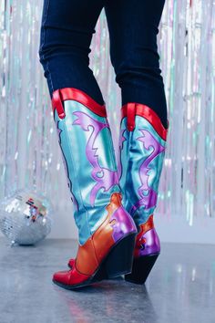 These colorful boots are a show stopper and will have you standing out in the crowd! They are meant for a fabulous party so if you are going to the big easy these cuties are a must! These bold boots consist of a teal shaft with a purple flame design on the front and back shaft plus the heel, a red trimmed top with pull tabs and red pointed toe, and an orange vamp that extends around the heel. Shaft height: 15" 15" calf opening Heel height: 3" Fits true to size ﻿ *Screen resolution/lighting may a Multicolor Retro Boots For Fall, Retro Multicolor Boots For Fall, Retro Multicolor Boots For Winter, Multicolor Western Boots For Spring, Retro Boots For Spring Party, Retro Spring Party Boots, Multicolor High Ankle Party Boots, Trendy Multicolor Party Boots, Fitted Multicolor Snip Toe Boots