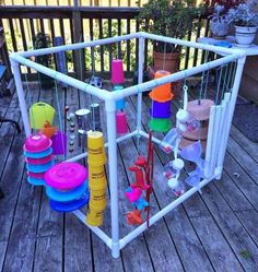 an outdoor play structure made out of plastic cups and saucers on a deck with potted plants in the background