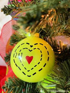 a yellow ornament with a red heart on it hanging from a christmas tree