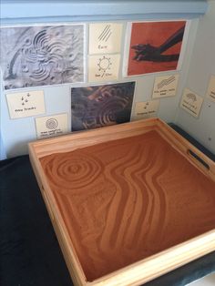 a large wooden box sitting on top of a table next to papers and pictures hanging on the wall