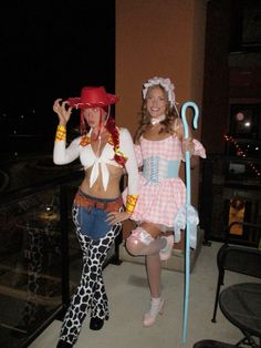 two women dressed in costumes standing next to each other on a balcony at night time