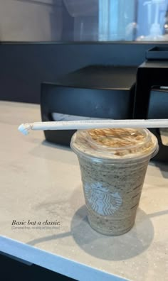 a starbucks drink sitting on top of a counter with a straw in it's cup