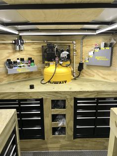 the inside of a workbench with tools and supplies on it, including a yellow propane tank