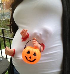 a pregnant woman wearing a halloween costume and holding a pumpkin shaped bag with blood on it