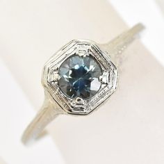 A 1920's mold was utilized in this faithful vintage reproduction engagement ring. Petite filigree in white gold set with a natural Montana Sapphire Other information: center stone: round-cut natural Montana Sapphire weighing .47 carats Recycled 14 karat white gold Finger size US 6 1/4* Made from vintage methods and instruments in recycled gold by Hugo Kohl and team in his Harrisonburg, VA studio. *This ring can be re-sized to sizes ranged 5-8 at no extra charge. If you would like to have this ri Victorian Sapphire Ring With Diamond Cut, Vintage Sapphire Ring In 14k White Gold, Vintage Sapphire Ring In 14k White Gold, Round Cut, Vintage 14k White Gold Sapphire Ring With Round Cut, Vintage 14k White Gold Round Sapphire Ring, Vintage 14k White Gold Sapphire Ring With Center Stone, Silver Milgrain Rings With Round Cut, Silver Rings With Milgrain Details In Round Cut, Silver Rings With Milgrain Detail