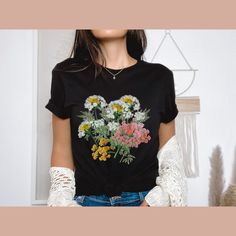 Introducing our Wildflowers T-Shirt, a blossoming beauty that captures the essence of nature's vibrant colours. This floral-inspired tee is designed for ladies who appreciate the delicate charm of wildflowers. It's the perfect gift for women, whether it's for your best friend or a dear friend who loves floral motifs. Our premium t-shirt is crafted with utmost care, ensuring both comfort and softness. Made from 100% cotton, it offers a luxurious feel against your skin. The heather colours feature a blend of 52% cotton and 48% polyester, combining durability and style in one. Fabrication: *Solid colours: Crafted with 100% cotton for a luxurious feel *Heather colours: Blending 52% cotton and 48% polyester for durability and comfort *Light fabric material that runs true to size, providing a pe Spring Floral Print Graphic Tee, Spring Printed Tops For Gift, Printed Tops For Spring Gift, Printed Tops For Spring, Spring Botanical T-shirt With Floral Design, Spring Graphic Print Tops Gift, Spring Botanical Graphic Print T-shirt, Spring Graphic Print Tops As Gift, Spring Black T-shirt With Floral Print