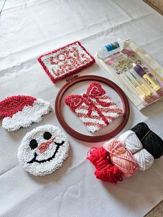 some crocheted items are laying out on a white tablecloth with red and white yarn