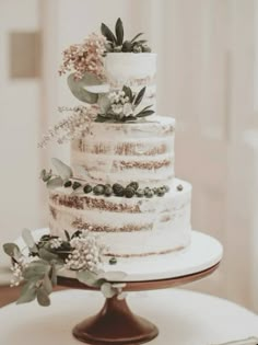 a white wedding cake with greenery on top