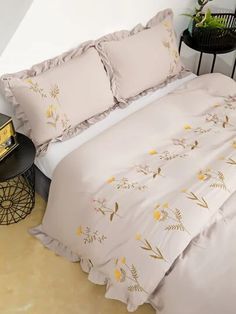 a bed with yellow flowers on it in a room next to a table and chair