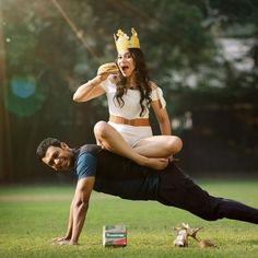 a man holding a woman on his back in the grass while they both wear crowns