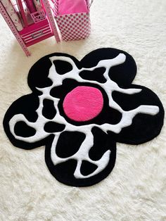 a black and white flower rug with pink center on the floor next to a chair