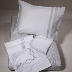 a bed with white sheets and pillows on top of each other in front of a wall