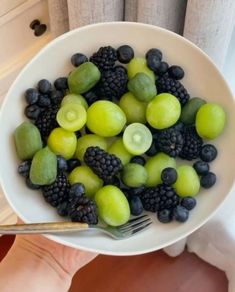 a white bowl filled with green and black fruit