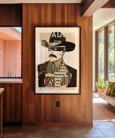 a poster hanging on the wall in a room with wood paneling and large windows