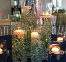 candles and flowers in glass vases on a blue table cloth with chairs around it